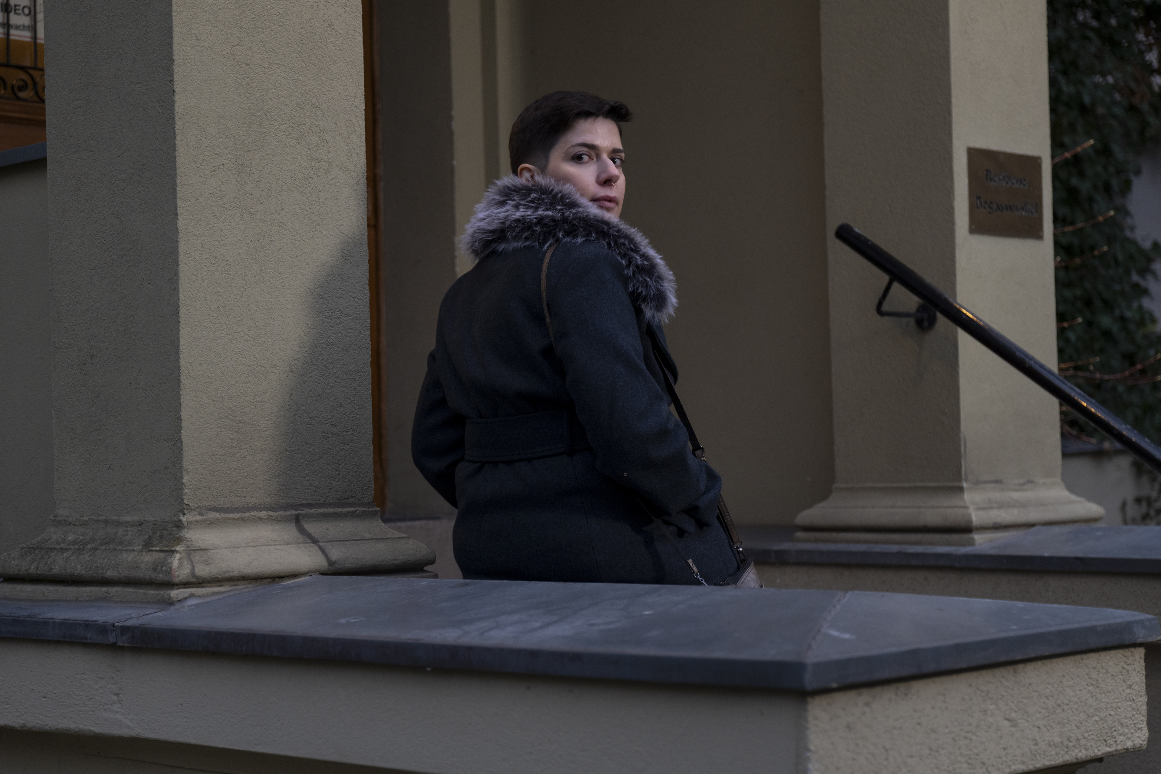 Rachel Gregor lehnt an einem Sockel und dreht sich zur Kamera um