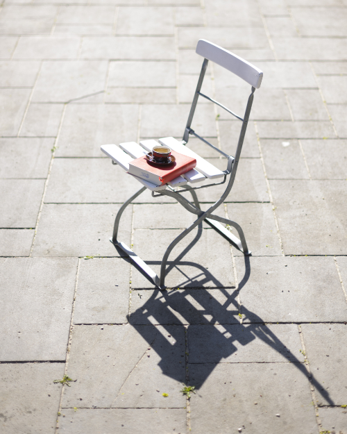 White garden chair with book and coffee mug