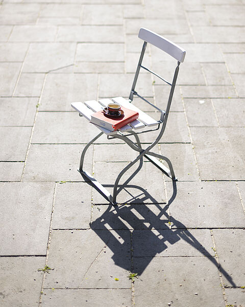 Espresso und Buch auf einem Stuhl