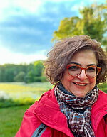 Mina Akbari Frau mit Brille auf einer grünen Wiese vor einem blauen Himmel