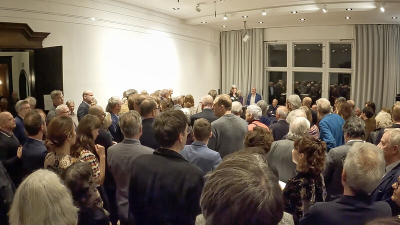 A room full of people standing with the back to the camera